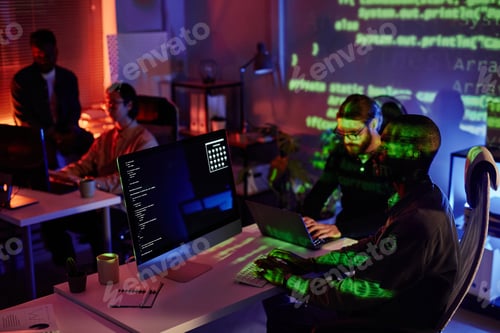 Preview: Group of young intercultural coworkers sitting by desks in front of computers