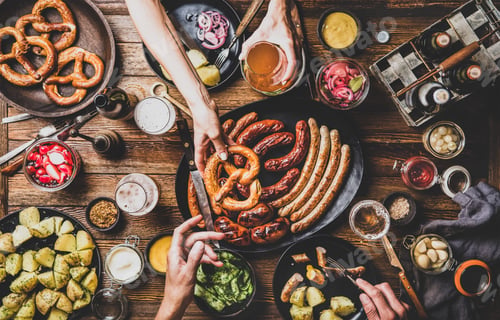 Preview: Octoberfest party dinner table with beer, snacks and peoples hands