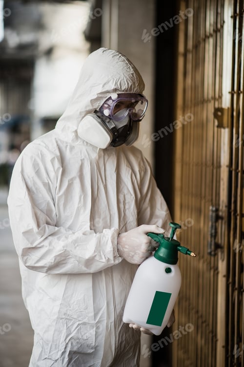 Preview: Man in protective suit and mask sprays disinfectant