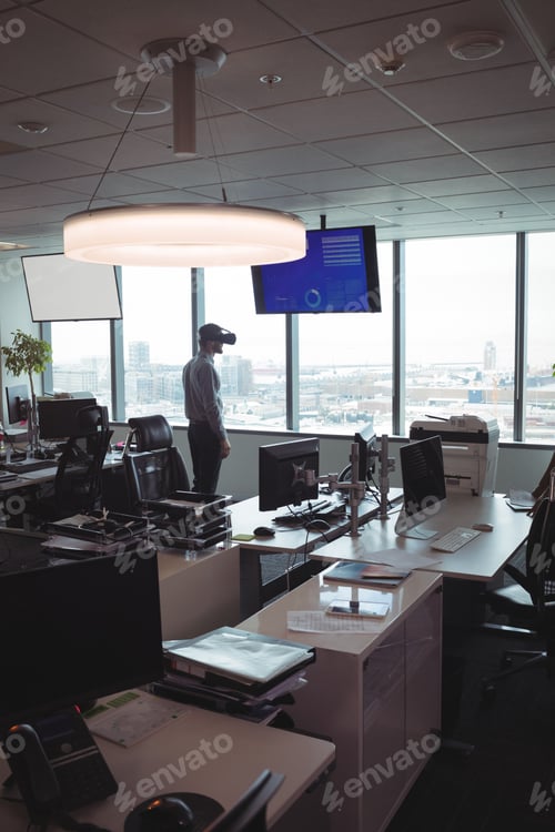 Preview: Businessman using virtual reality glasses by desk