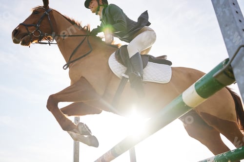 Preview: Galloping ahead. Shot of a young rider jumping over a hurdle on her horse.