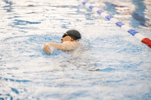 Preview: Man an in hat swimming in indoors swimming pool breaststroke