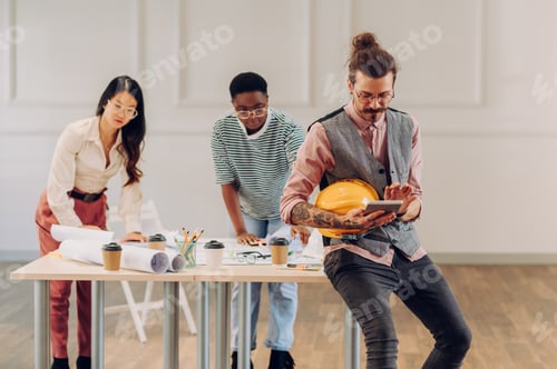 Preview: Male architect using blueprint and tablet in an office during a meeting
