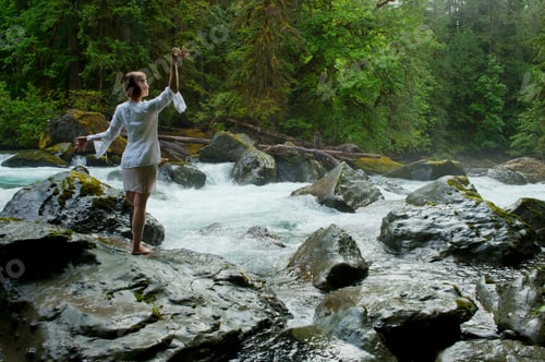 Preview: Woman meditating on rock by water