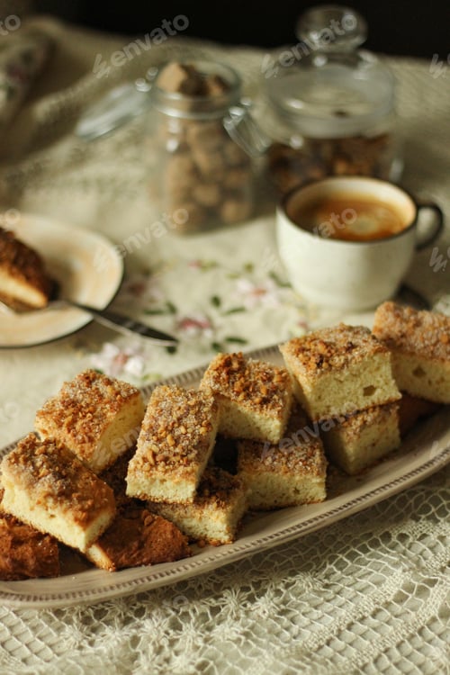 Preview: Cookies with nuts and sugar lie on a dish on the table next to a cup of coffee