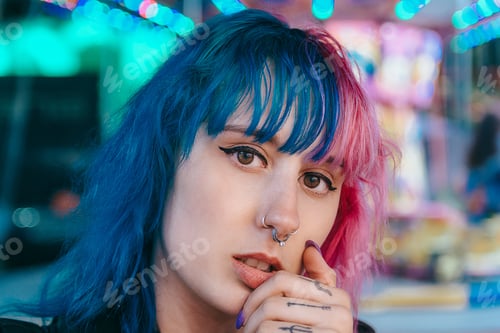 Preview: Portrait of a young female with pink and blue hair with a serious facial expression
