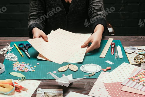 Preview: cropped image of designer choosing paper for scrapbooking postcard