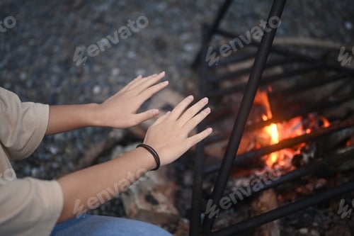 Preview: Young woman sitting near campfire in the forest.