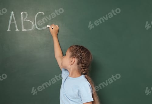 Preview: Little school child writing with chalk on blackboard