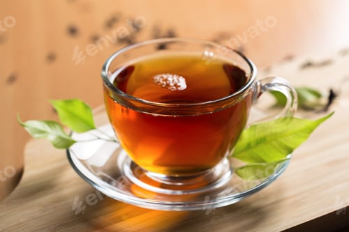 Preview: Freshly brewed tea served in a glass cup with green leaves on a wooden surface