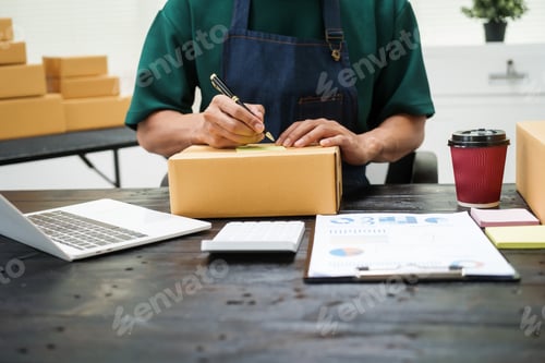 Preview: A man is working at his desk, preparing parcel boxes for shipment. He checks packs items carefully