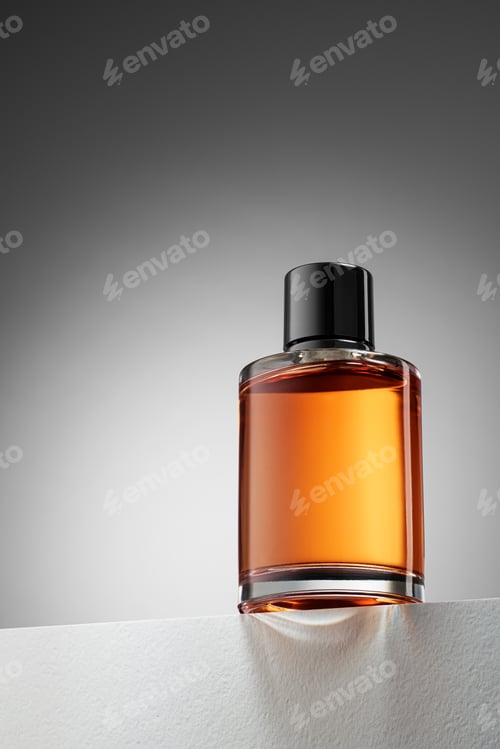 Preview: Amber liquid in a glass perfume bottle catching light on a white surface.