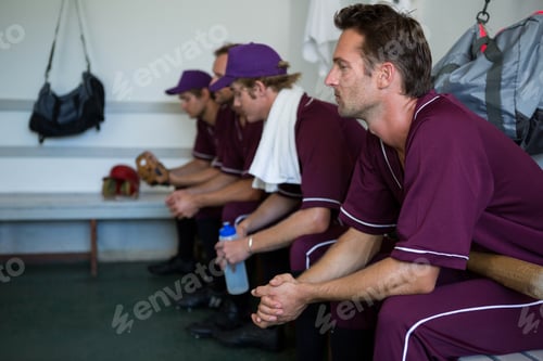 Preview: Side view of tired basball players sitting on bench