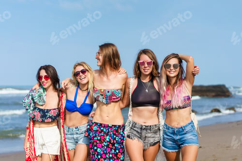 Preview: group of happy young women in bikini spending time together on beach