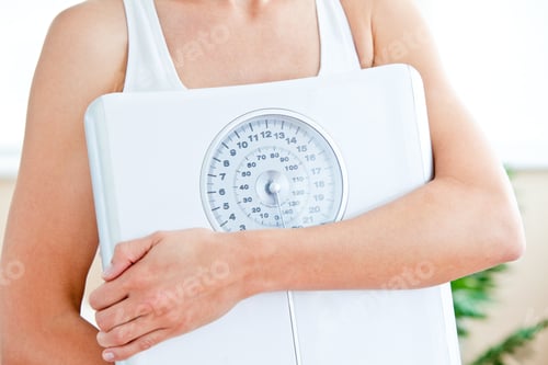 Preview: Close-Up Of A Hispanic Woman Holding A Scale In Her Living-Room At Home