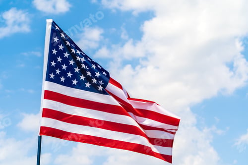 Preview: American flag waving in the wind against blue sky