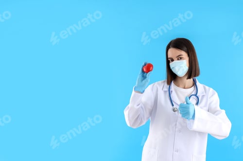 Preview: Woman Doctor Holding Heart Model on Blue Background