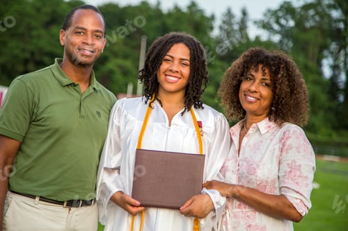 Preview: Portrait of teenage girl with parents at graduation ceremony
