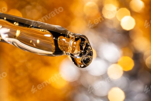 Preview: Liquid serum and dropper on a bokeh golden background macro. 24k gold Serum drop