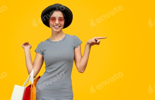 Preview: Smiling lady with paper bags pointing aside