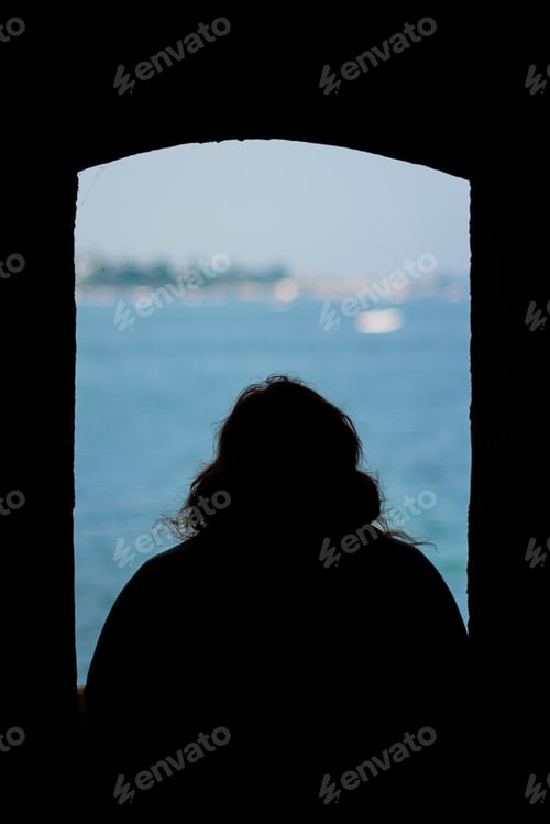Preview: Silhouette of person watching calm seascape through an open window