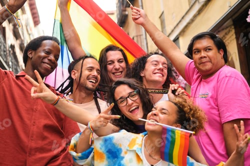Preview: Happy group of LGBTQ people smiling and laughing with rainbow flags.