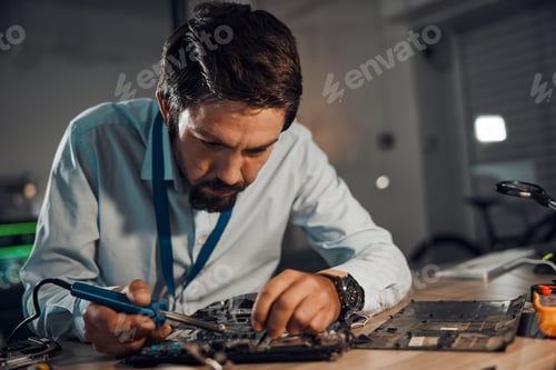 Preview: Concentration man, it or soldering motherboard in engineering workshop for night database fixing. T