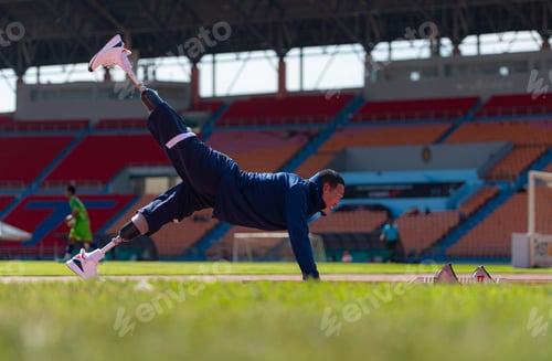 Preview: Disabled athletic man stretching and warming up before running on stadium track