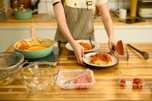 Preview: Young woman preparing a homemade pasta dish on wooden countertop