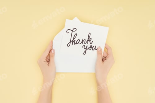 Preview: cropped person holding paper with thank you lettering isolated on yellow background