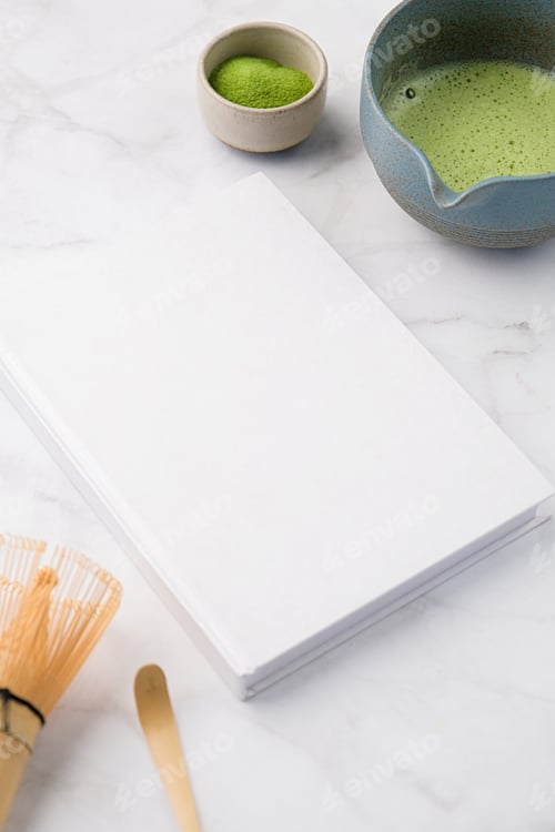 Preview: blank book mockup on on white table with green matcha tea