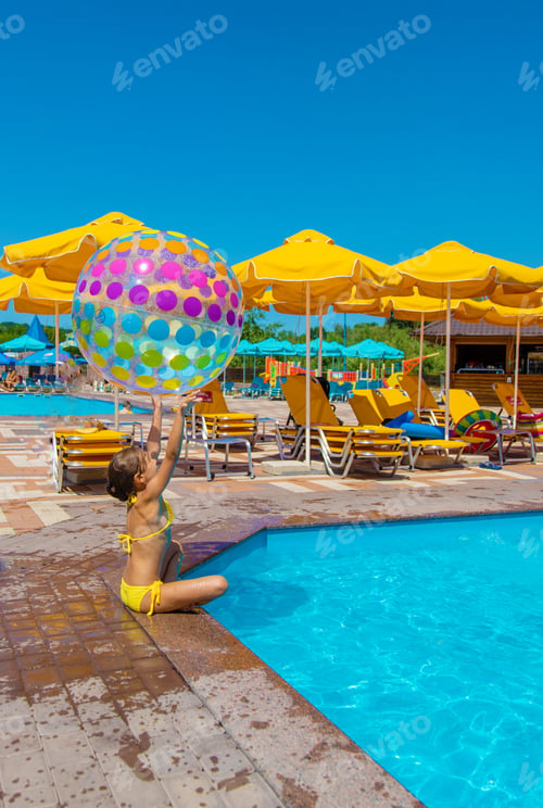 Preview: The child plays with a ball in the pool. Selective focus.