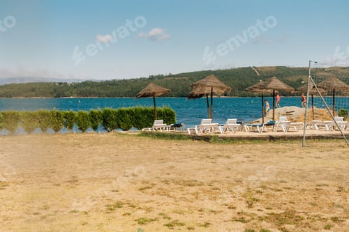 Preview: Natural solarium with deck chairs and straw parasols near the river