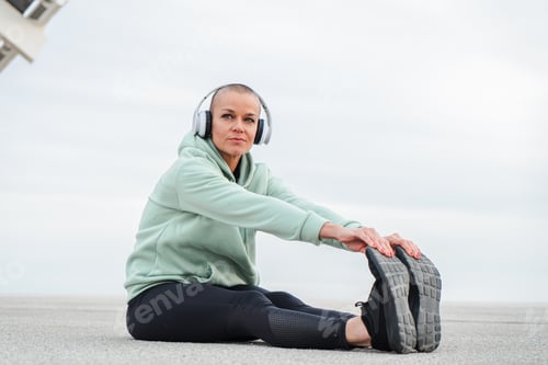 Preview: Mature Woman Stretching Her Legs While Listening to Music with Headphones on, Embracing a Sporty