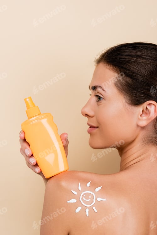Preview: young woman with bottle of sunblock and image of happy sun on shoulder isolated on beige