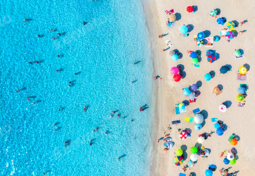 Preview: Aerial view of colorful umbrellas on beach, people in blue sea
