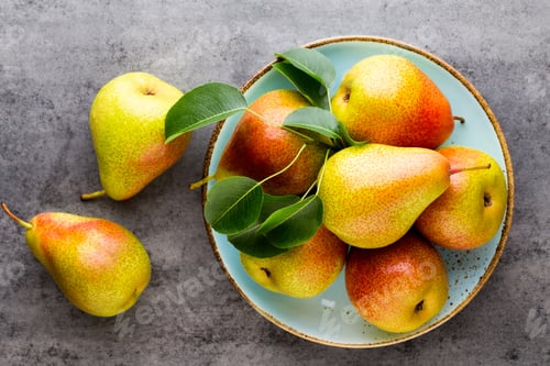 Preview: Fresh bio pear with leaves on the plate. Gray stone table.