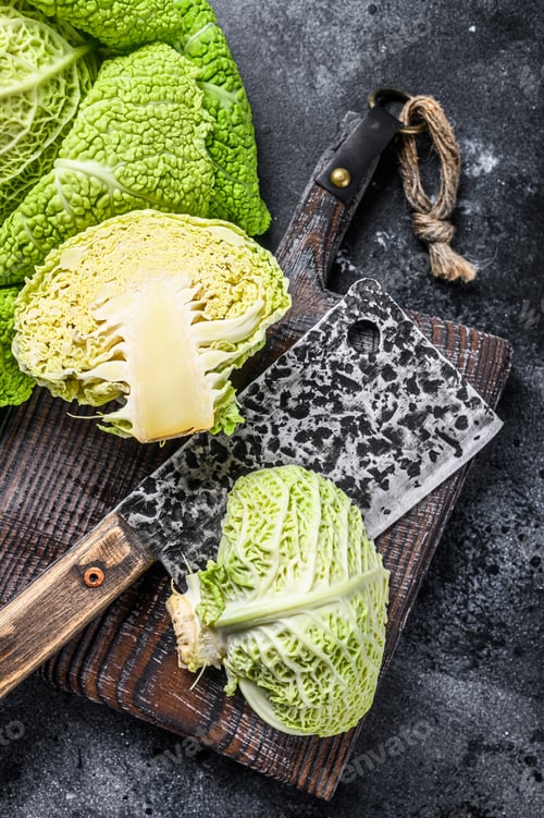 Preview: Cut Fresh healthy savoy cabbage on cutting board. Black background. Top view