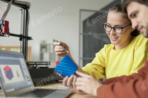 Preview: Young contemporary designers discussing blue plastic object in front of laptop