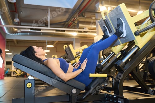 Preview: Woman exercising on leg press machine in gym