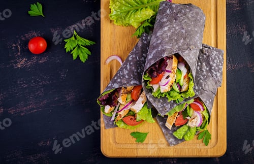 Preview: Tortilla with added ink cuttlefish wraps with chicken and vegetables on white background.