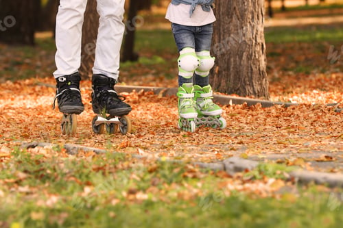 Preview: Father and his daughter roller skating in autumn park
