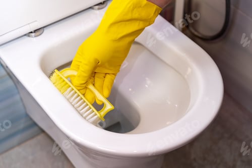 Preview: Woman washing and disinfecting toilet bowl with detergent close-up.