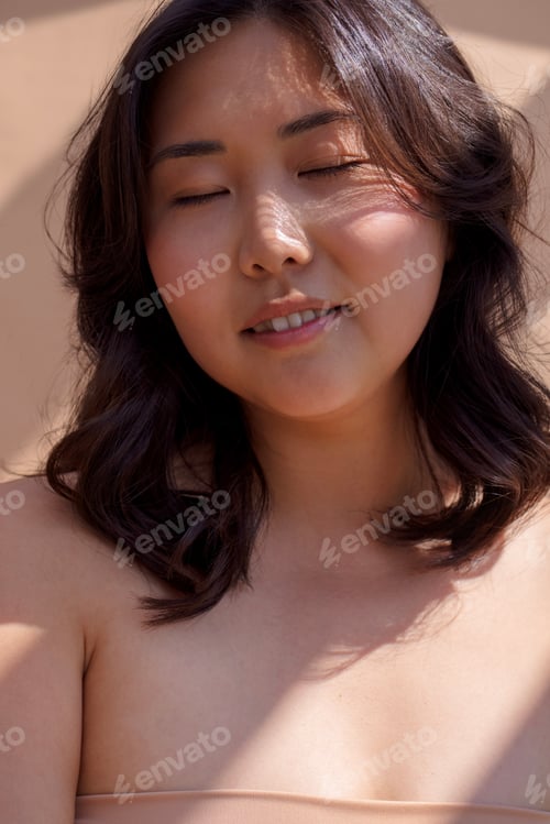 Preview: Asian woman with closed eyes, enjoying sunlight, showcasing natural beauty