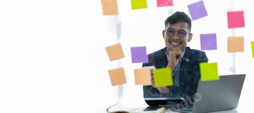 Preview: Businessman thinking and planning work with sticker on glass plate in office.