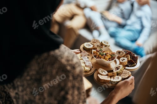 Preview: Close-up of Muslim woman serving dessert to her family at home.