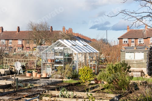 Preview: Allotment gardening in the month of March. View over plots with greenhouses, sheds and raised beds,