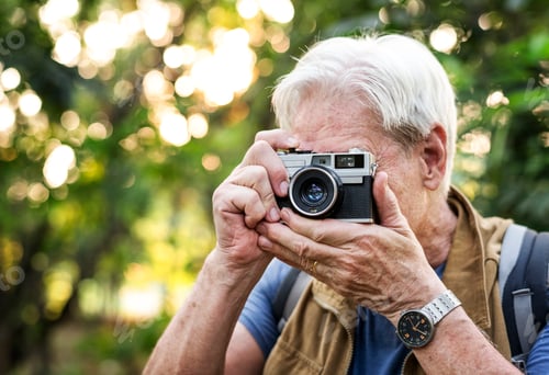 Preview: Senior trekker taking a photo with a film camera