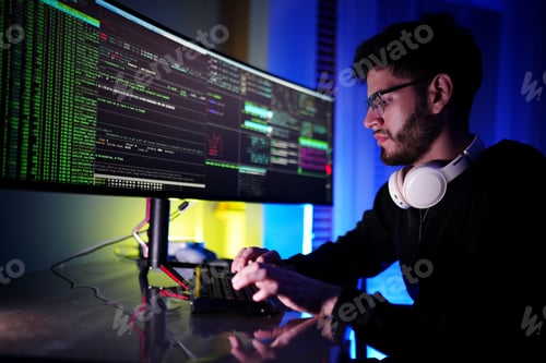 Preview: Young developer working on coding project in a modern workspace with dual monitors during nighttime