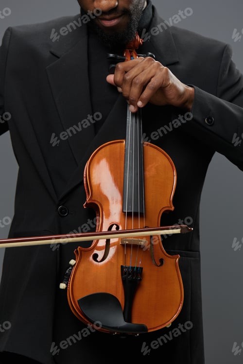 Preview: An elegant African American man in a suit holding a violin on a neutral gray background
